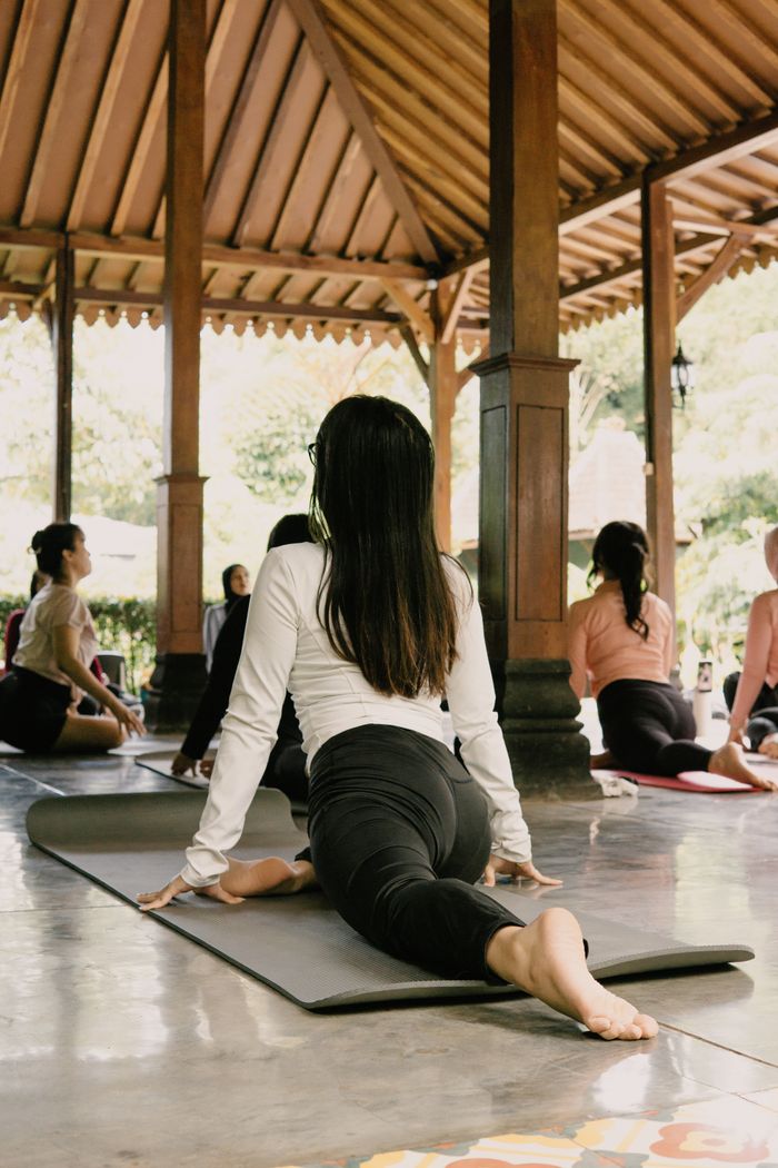 A diverse group practicing yoga in a serene outdoor pavilion in Indonesia.